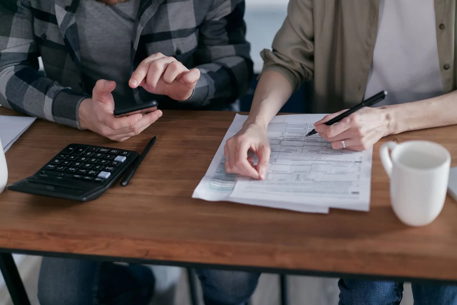 Dues persones revisen imports en documents al costat d'una calculadora sobre la taula