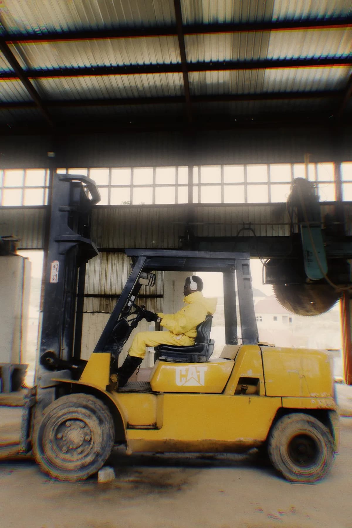 Persona amb vestuari i calçat laboral conduint un carretó elevador en una nau industrial