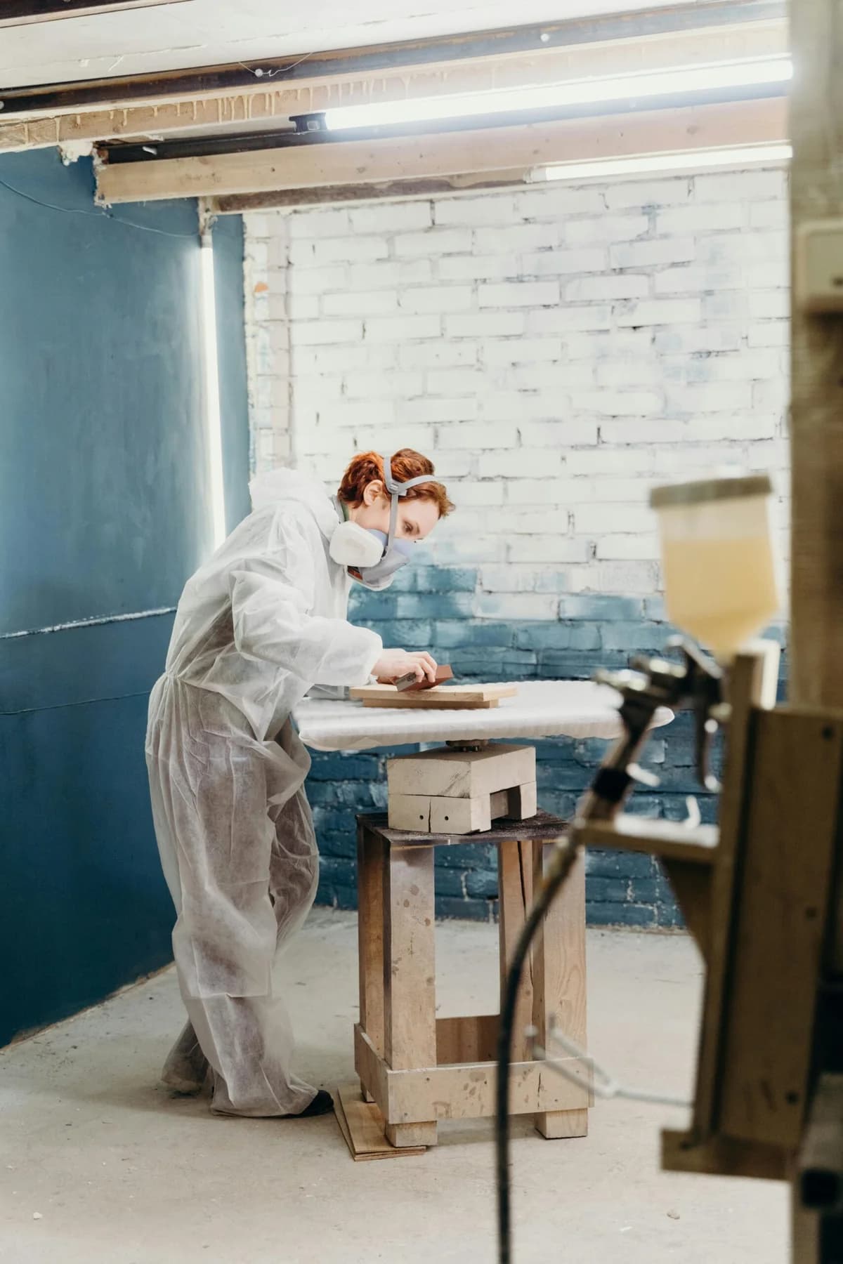 Preparació d'una peça amb poliment manual, amb una pistola de pintura en primer pla