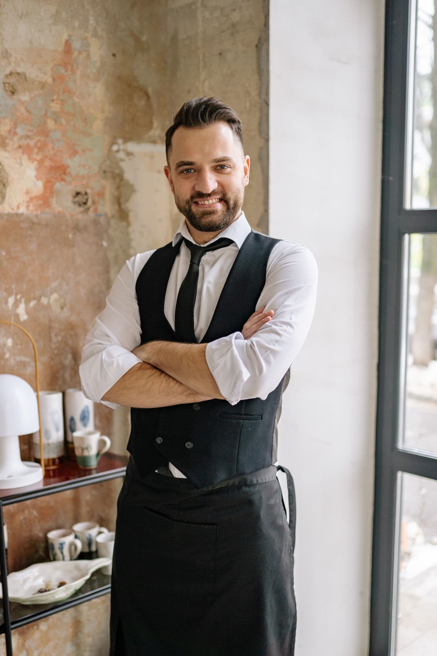Hospitality uniform: waiter wearing a white shirt, black waistcoat, tie and apron in a café