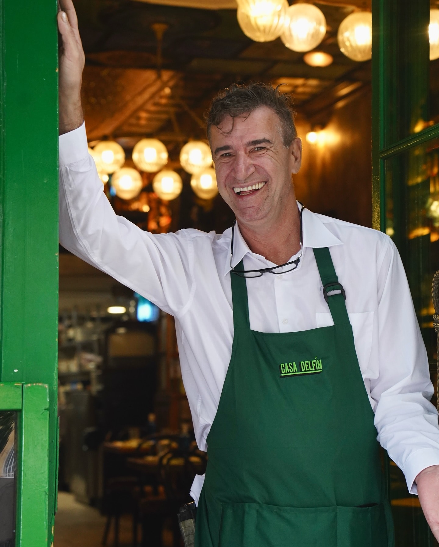 Camarero de Casa Delfín con camisa blanca y delantal verde personalizado con el logo del restaurante