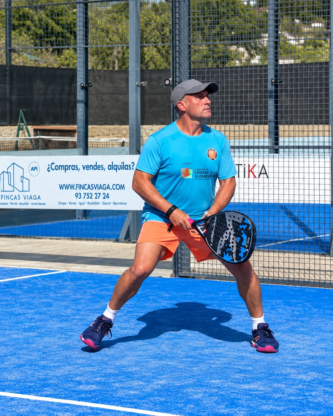 Jugador en una pista de pàdel blava amb la samarreta turquesa del torneig solidari a benefici de la Fundació Josep Carreras